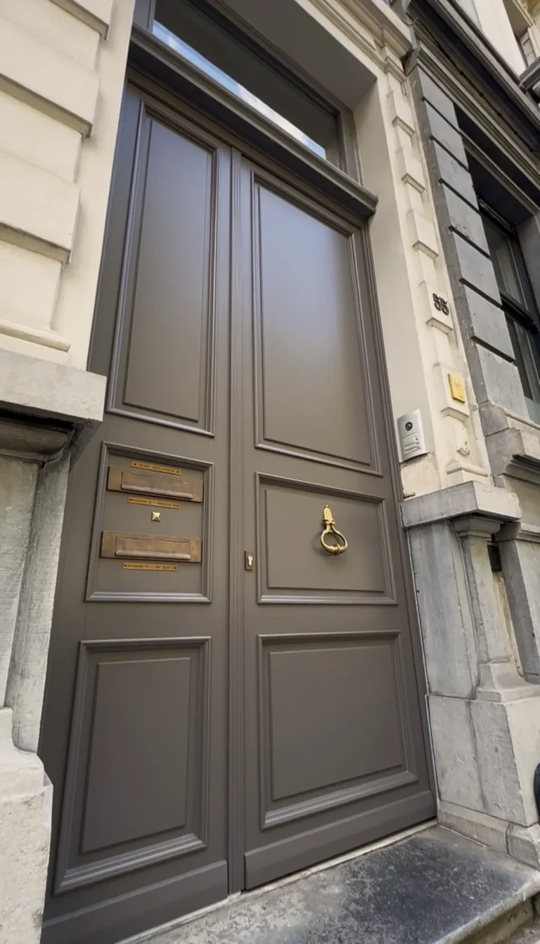 Grijze dubbele houten voordeur met koperen klopper in een herenhuis