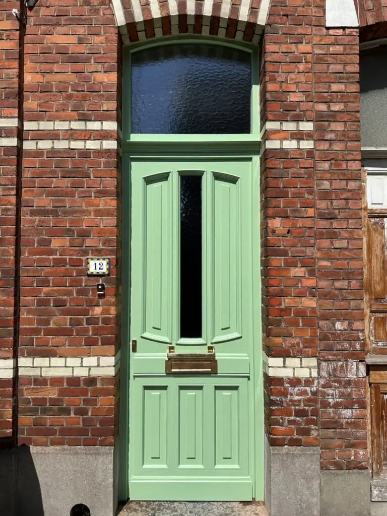 Groene houten voordeur met bovenlicht in een bakstenen gevel