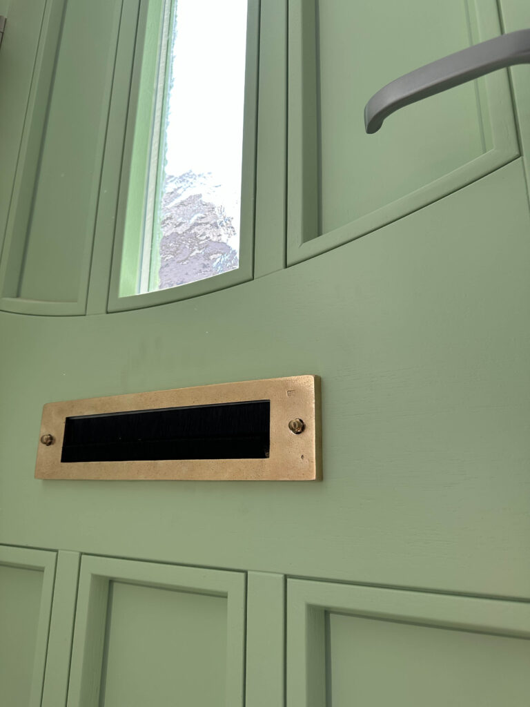 Groene houten voordeur met koperen brievenbus